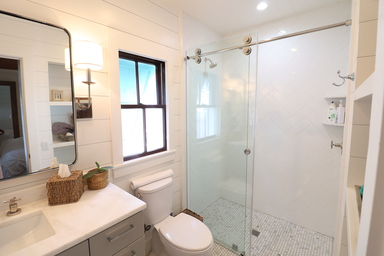 Walk-in shower with herringbone tile and frameless glass enclosure