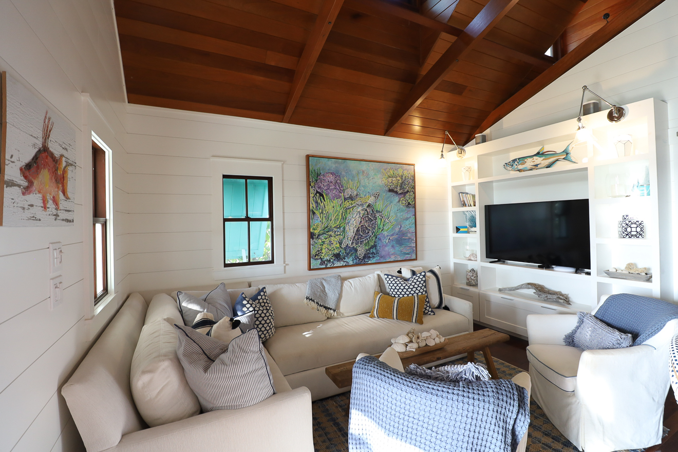 Cottage Two living room with cedar vaulted ceiling, sectional sofa, and colourful local artwork