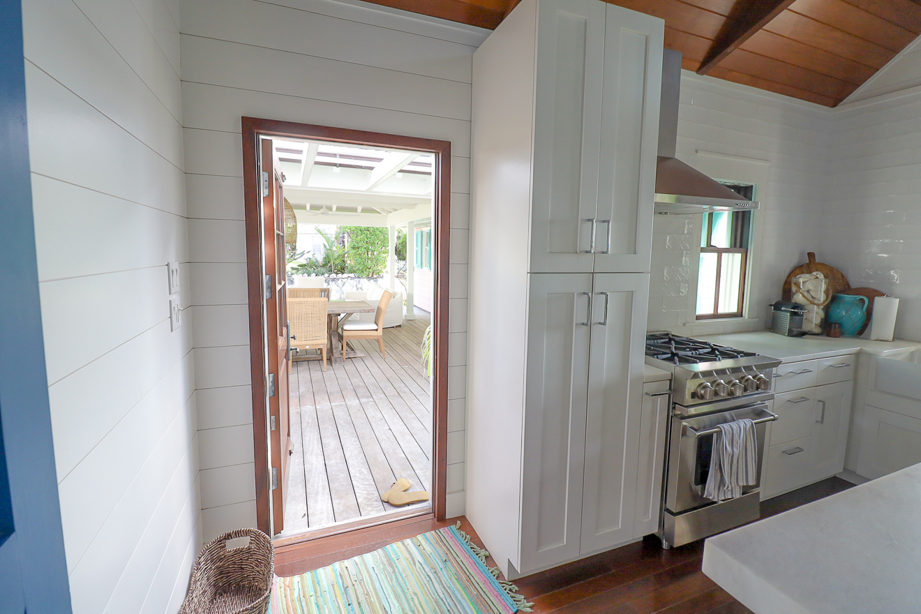 Cottage Two kitchen with white cabinets, shiplap walls, and door to the veranda