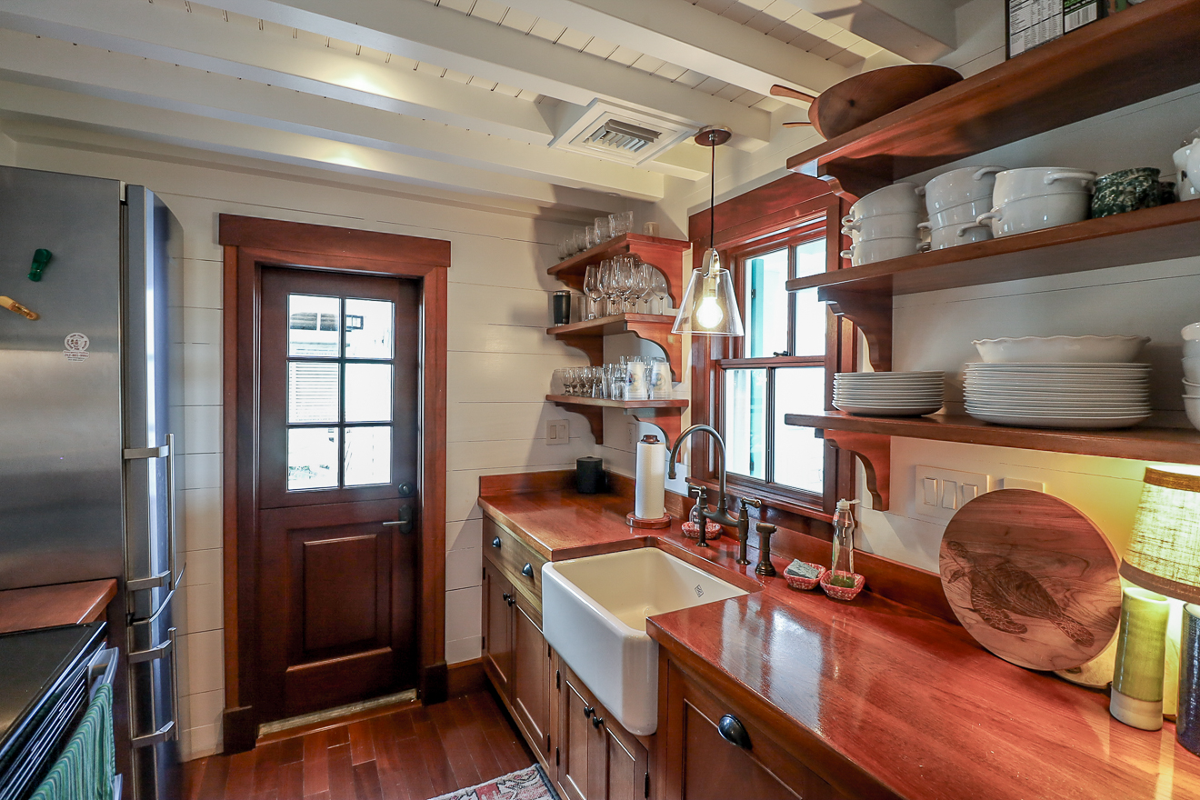 Cottage One galley kitchen with mahogany wood countertop, farmhouse sink, and open shelves