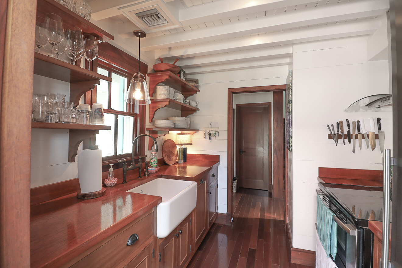 Full view of Cottage One's rustic kitchen with wood counters, shelving, and stainless appliances