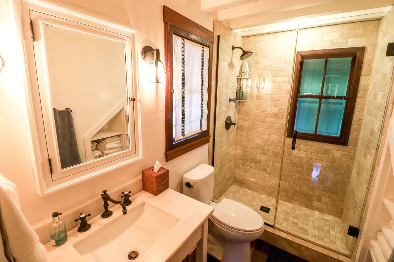 Cottage One bathroom with warm-toned tile, glass shower, and compact vanity
