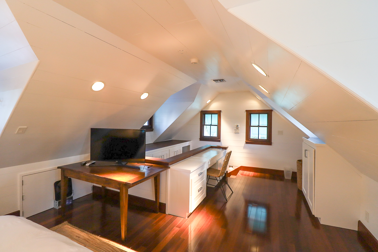 Cottage One loft bonus room with sloped ceiling, work desk, and TV