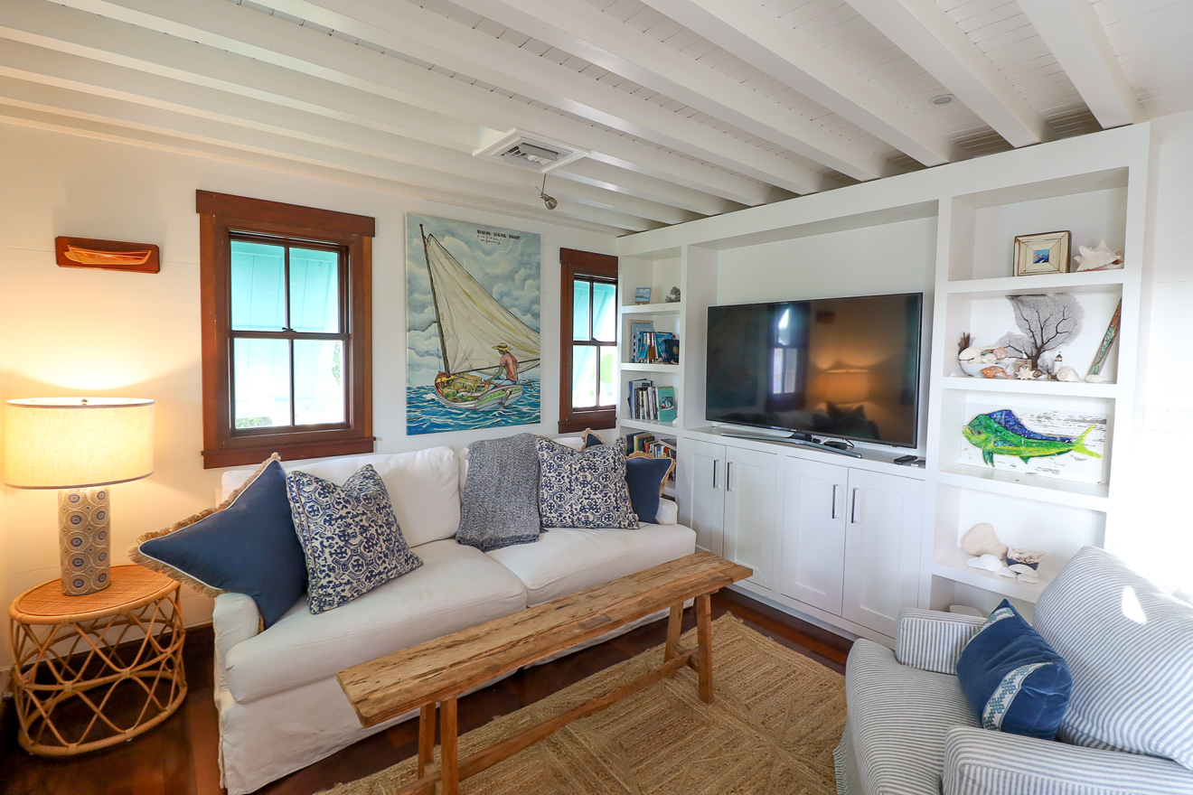 Cottage One living room with white coastal sofa, built-in TV unit, and artwork