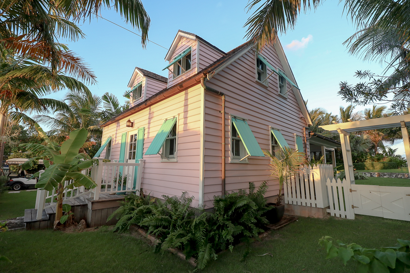 Cottage exterior with white picket fence and tropical landscaping