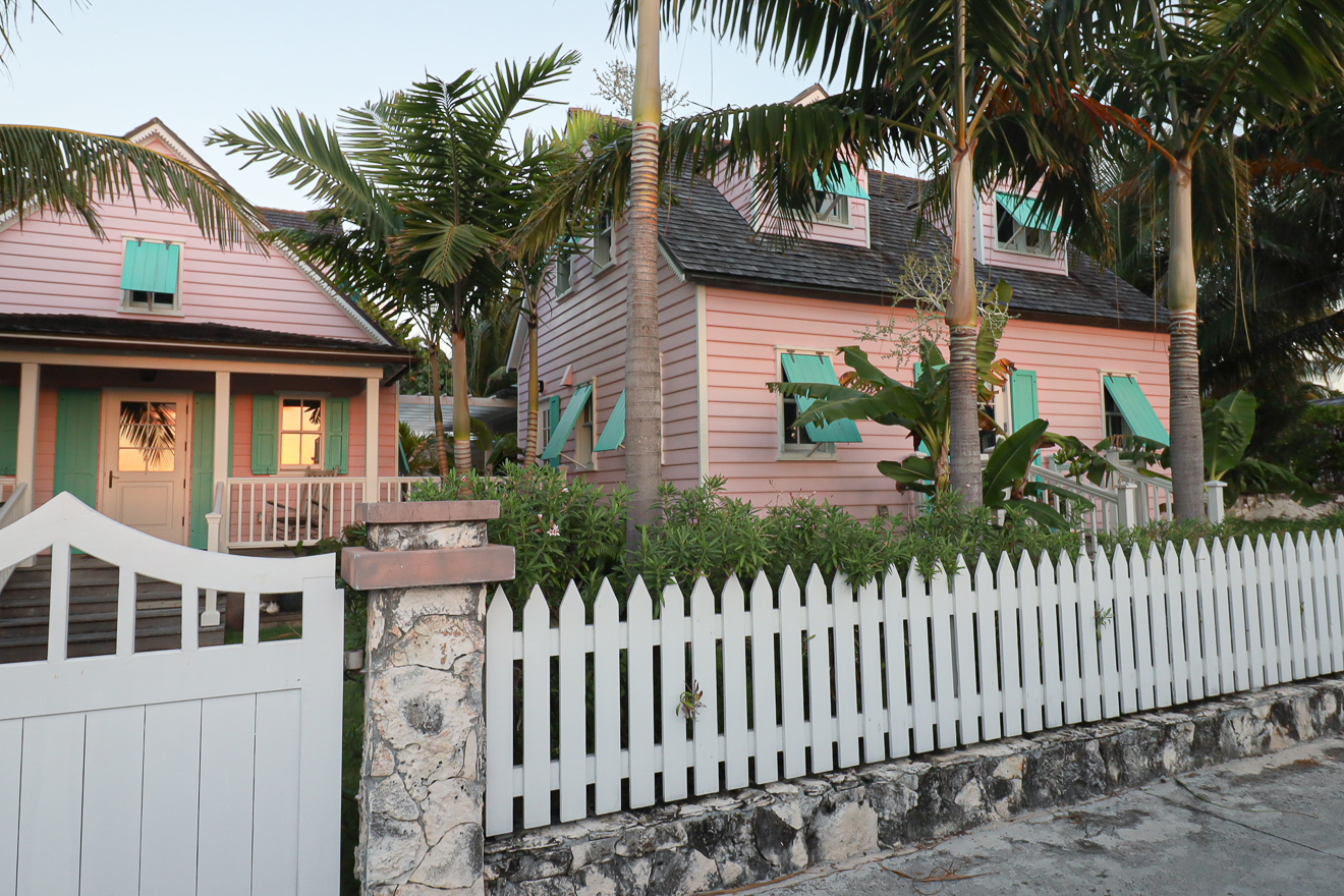 Cottages from the street at dusk, picket fence and palm trees